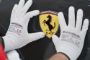 et par hænder med hvide handsker holder på et Ferrari-emblem