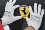 et par hænder med hvide handsker holder på et Ferrari-emblem