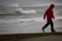 Mand på strand med frådende hav i baggrunden